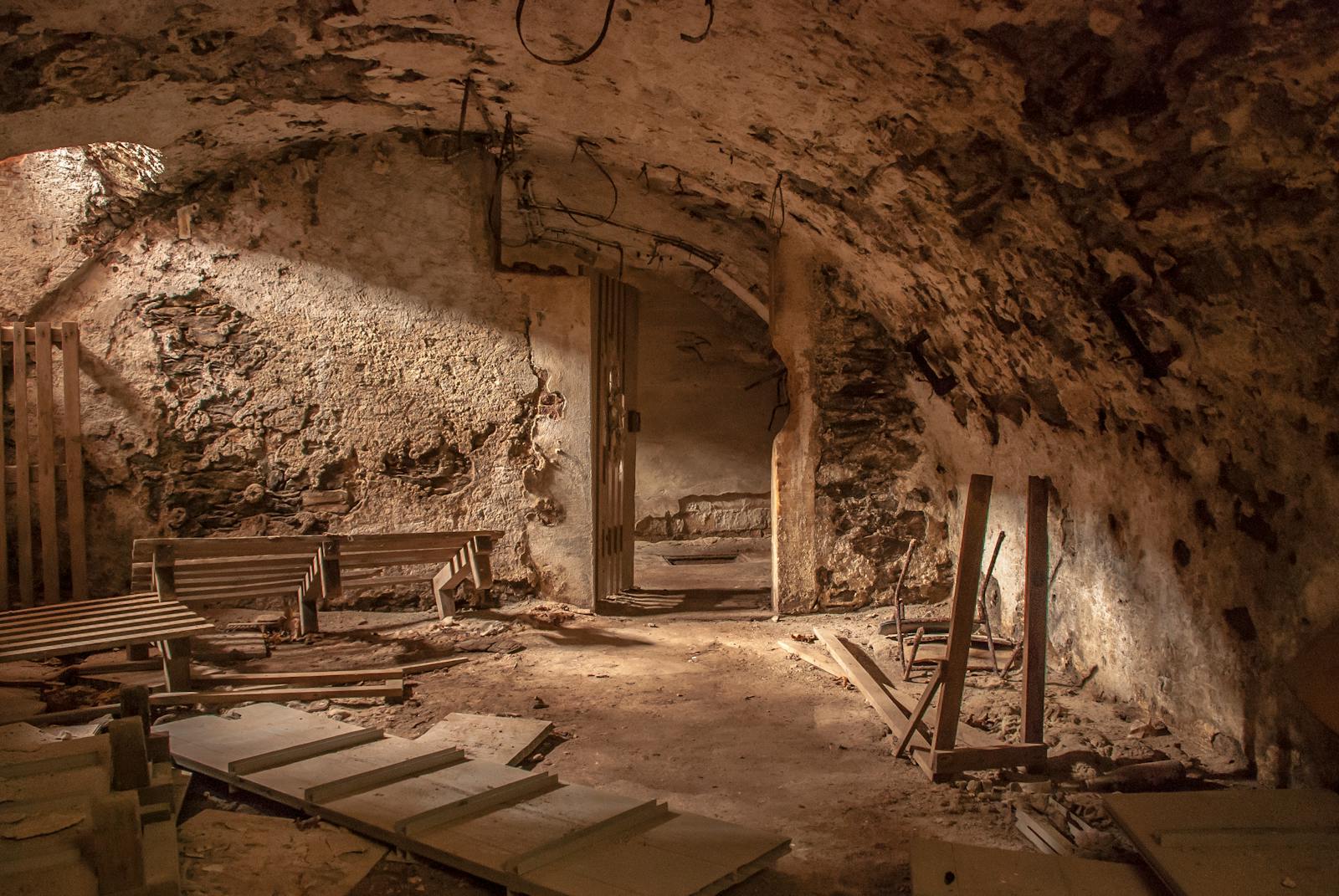 An atmospheric shot of an old, abandoned basement with weathered stone walls and scattered debris.