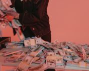 Bundles of US dollar bills on a table with a person organizing them.