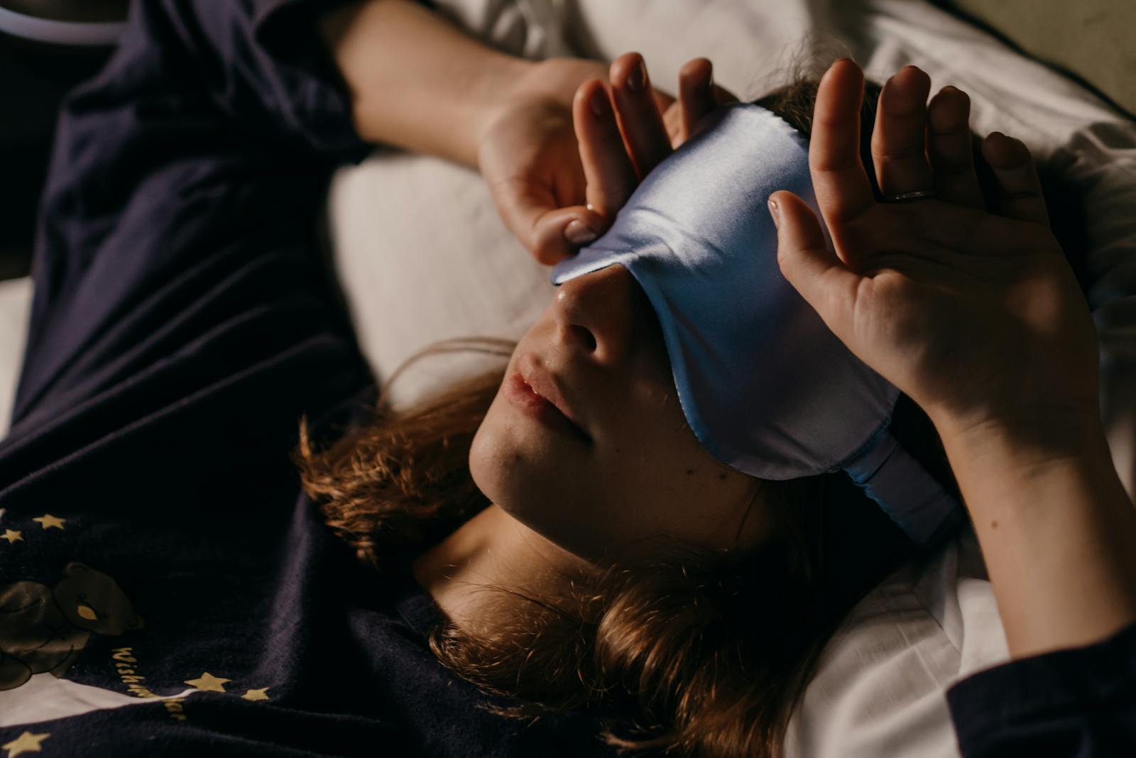 A woman resting at home wearing a sleep mask for a cozy afternoon nap.