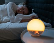Woman sleeping peacefully in a cozy bedroom with ambient bedside light.