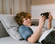 Young boy relaxing on a sofa, using a smartphone, indoors.