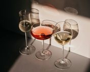Elegant arrangement of three wine glasses casting distinct shadows in warm light.