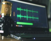 Close-up of a golden microphone and laptop used for audio editing.
