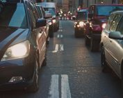 A congested city street lined with cars stuck in traffic at dusk, showcasing urban life.