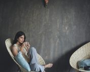 Woman sitting comfortably with a hot drink in a modern, minimalist setting.