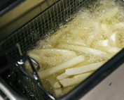 Close-up of french fries being deep-fried in a fryer, sizzling in oil.