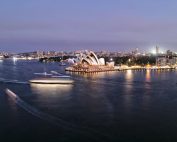 A stunning view of the Sydney Opera House and harbor illuminated at twilight, showcasing city life and architecture.