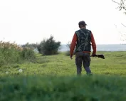 Lovac u zelenoj prirodi sa puškom preko ramena