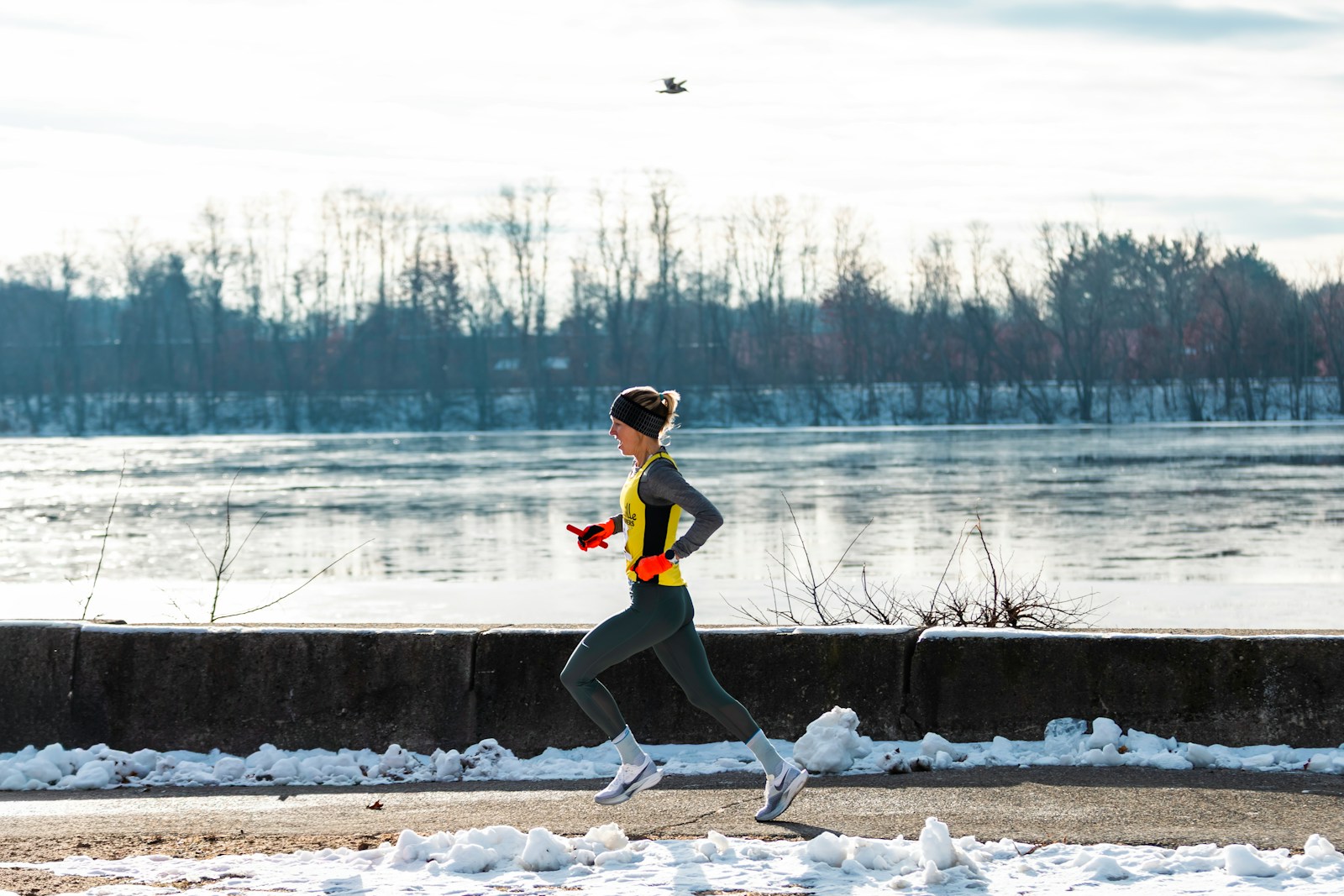 Woman running by a frozen river in winter