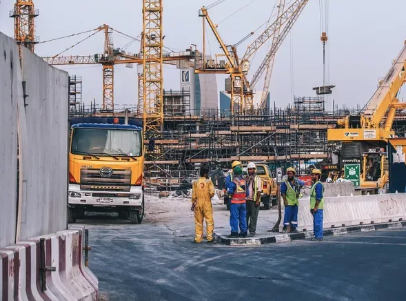 Radnici na gradilištu u Dubaiju sa kranovima i kamionom.