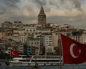 Panoramski pogled na Istanbul sa Galata kulom, brodom i turskim zastavama u prvom planu.