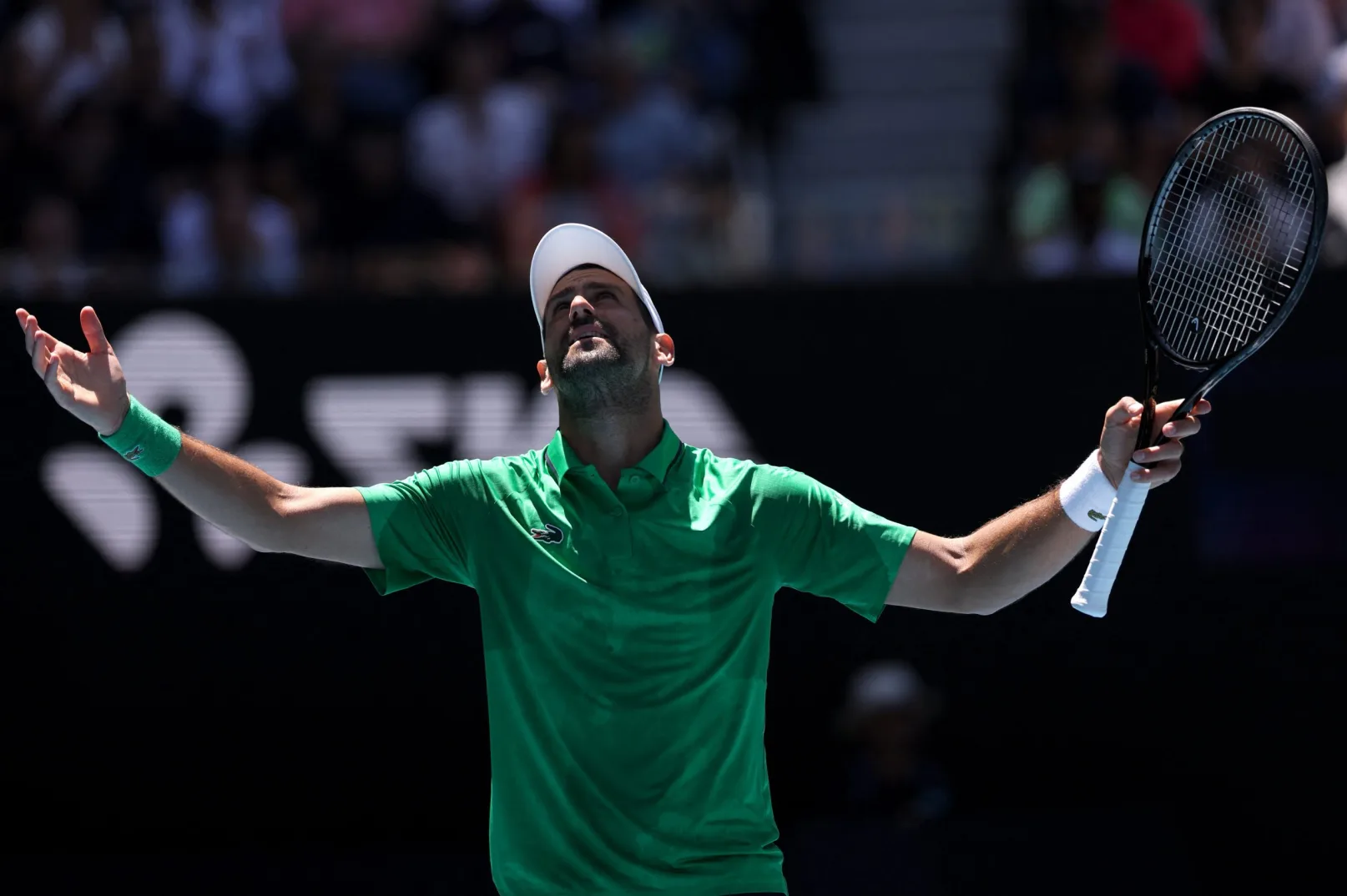 Novak Đoković slavi pobjedu na teniskom turniru, noseći Lacoste odjeću i držeći teniski reket.