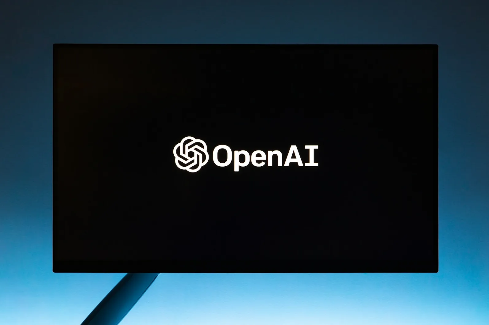Logo kompanije OpenAI na crnom ekranu monitora.