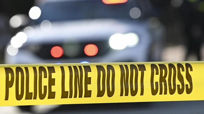 Žuta policijska traka sa natpisom 'POLICE LINE DO NOT CROSS' ispred zamagljene pozadine automobila.