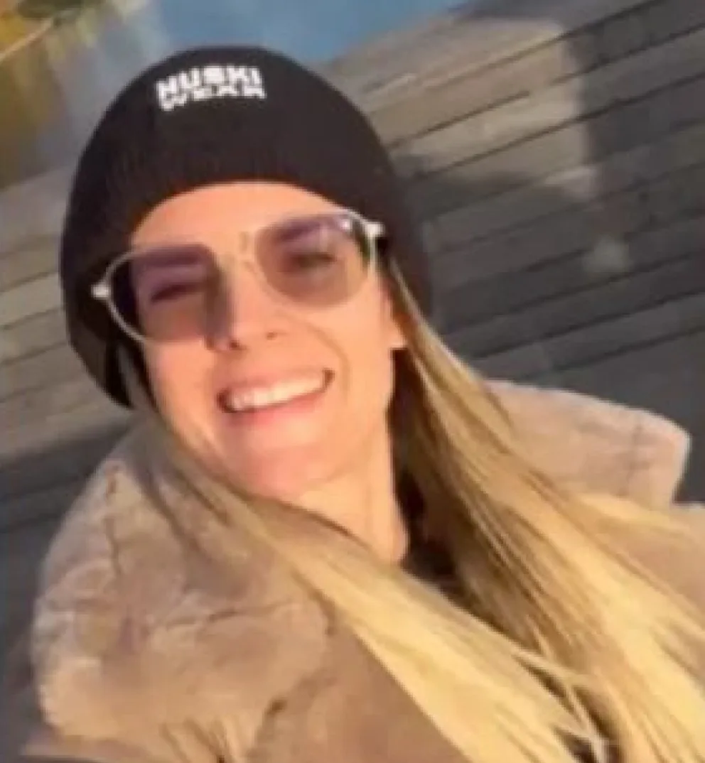 Portret nasmiješene žene sa plavom kosom, crnom kapom i naočarima za sunce.