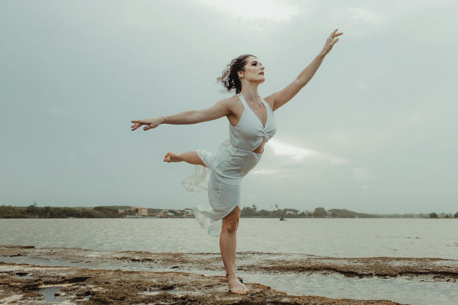 A woman in a ballet pose by the ocean expressing grace and freedom.