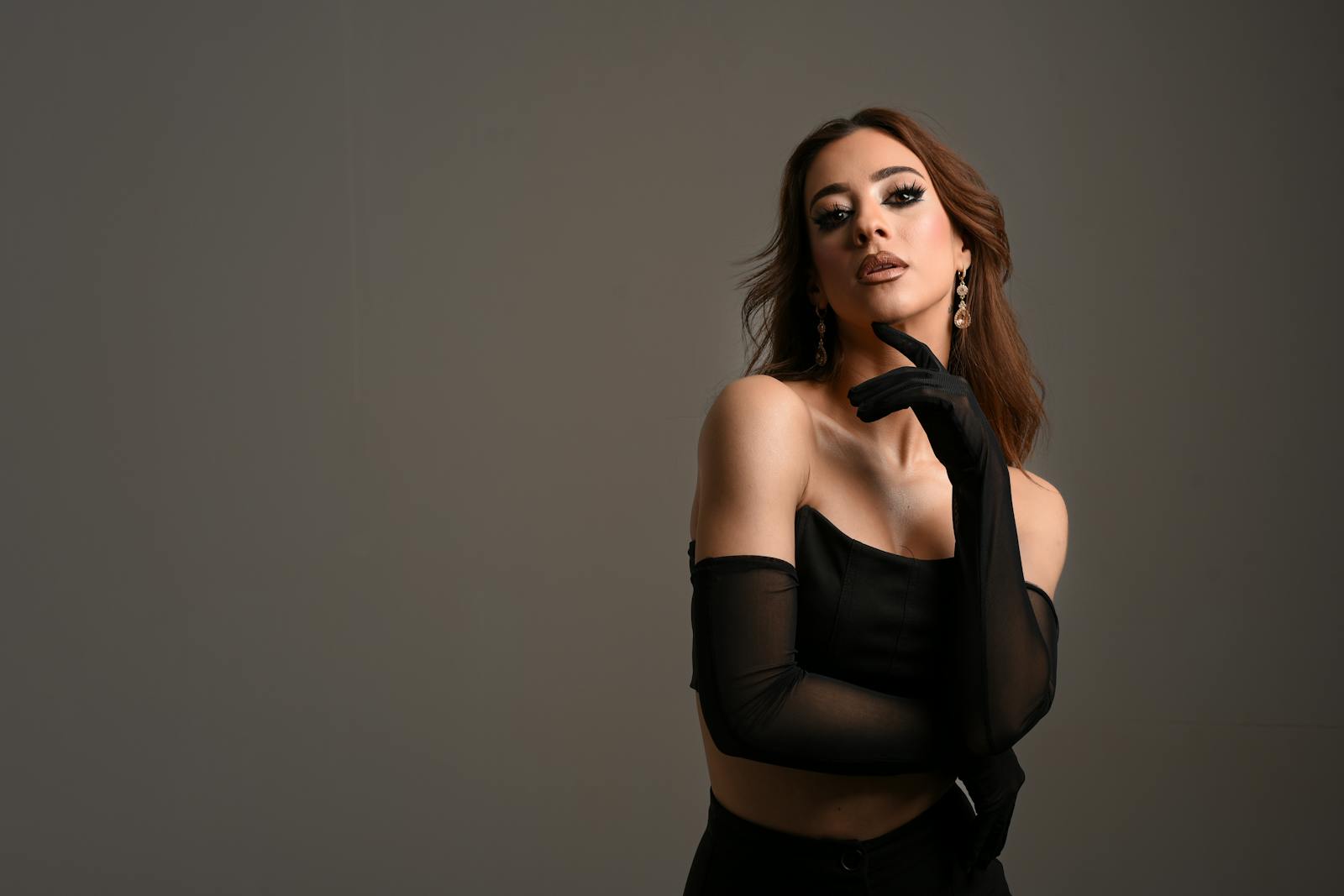 Stylish brunette woman posing in black attire in a studio setting.