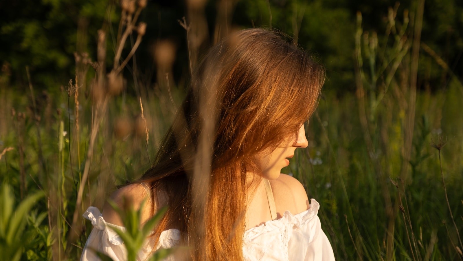 A woman in a white dress sitting in tall grass