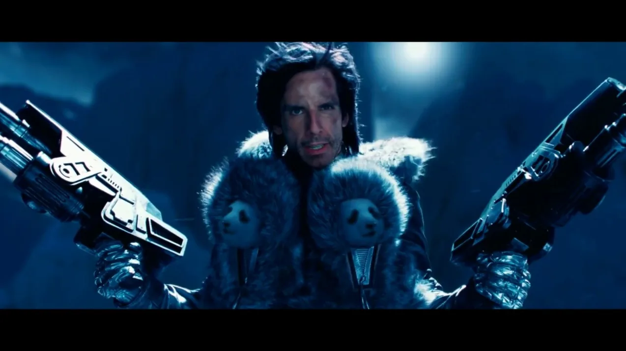 Ben Stiller u ulozi Zoolandera sa krznenom bundom na kojoj su prišivene glave pandi i drži dva futuristička oružja.