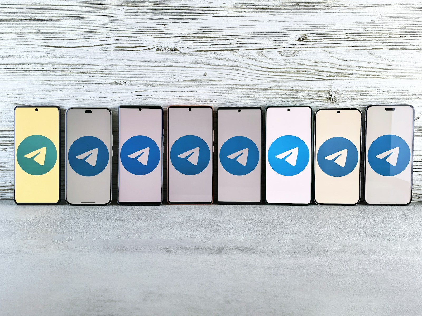 Seven smartphones with telegram logos in a row.