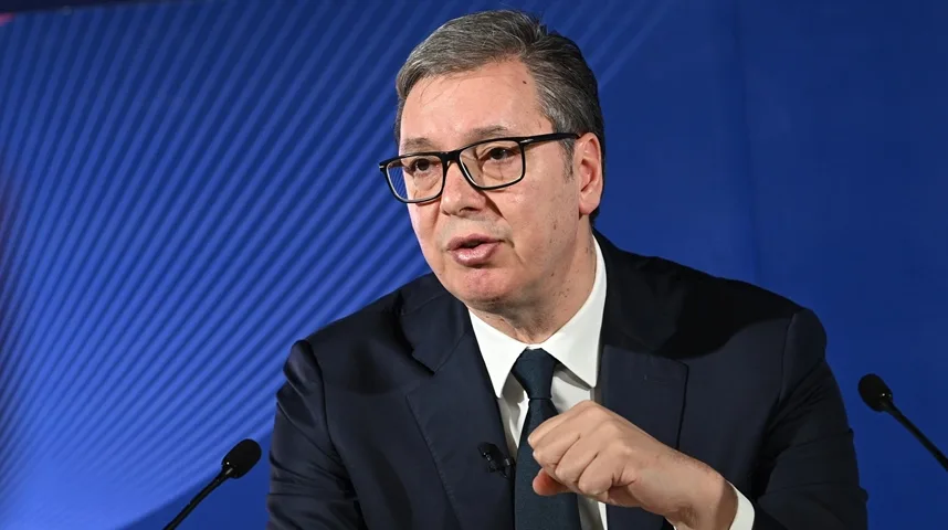 Aleksandar Vučić sa naočarima i tamnim odijelom govori pred mikrofonom.