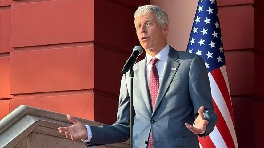 Američki izaslanik govori u mikrofon ispred američke zastave.