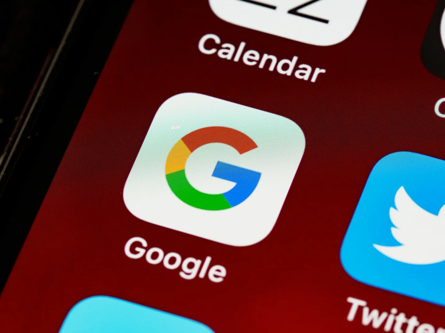 Ikona aplikacije Google na tamno crvenom ekranu pametnog telefona.