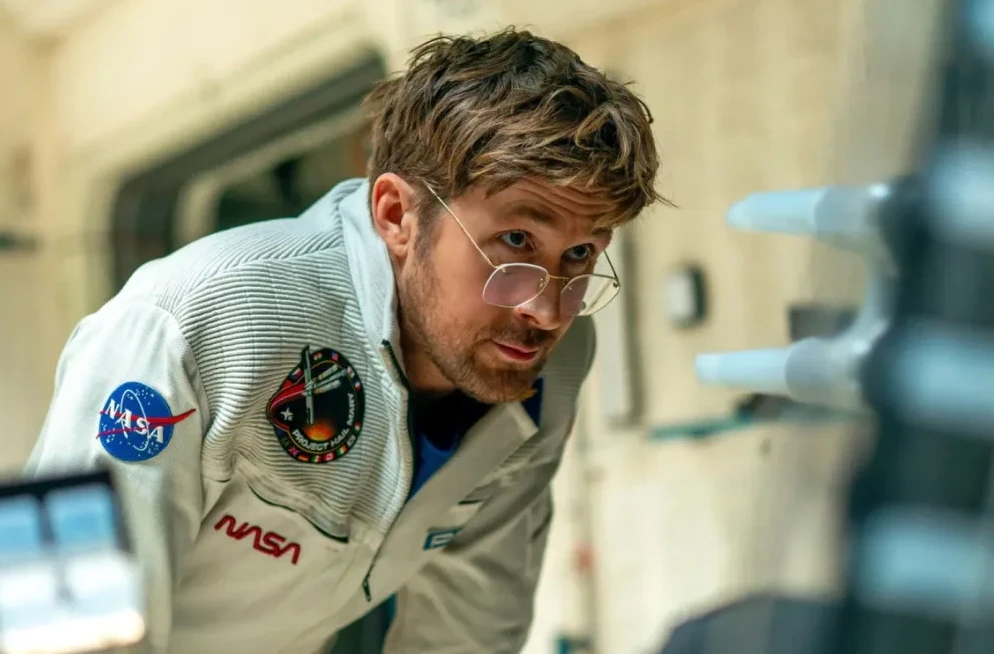 Astronaut u svemirskom odijelu s NASA-inim logom gleda u naučne instrumente.