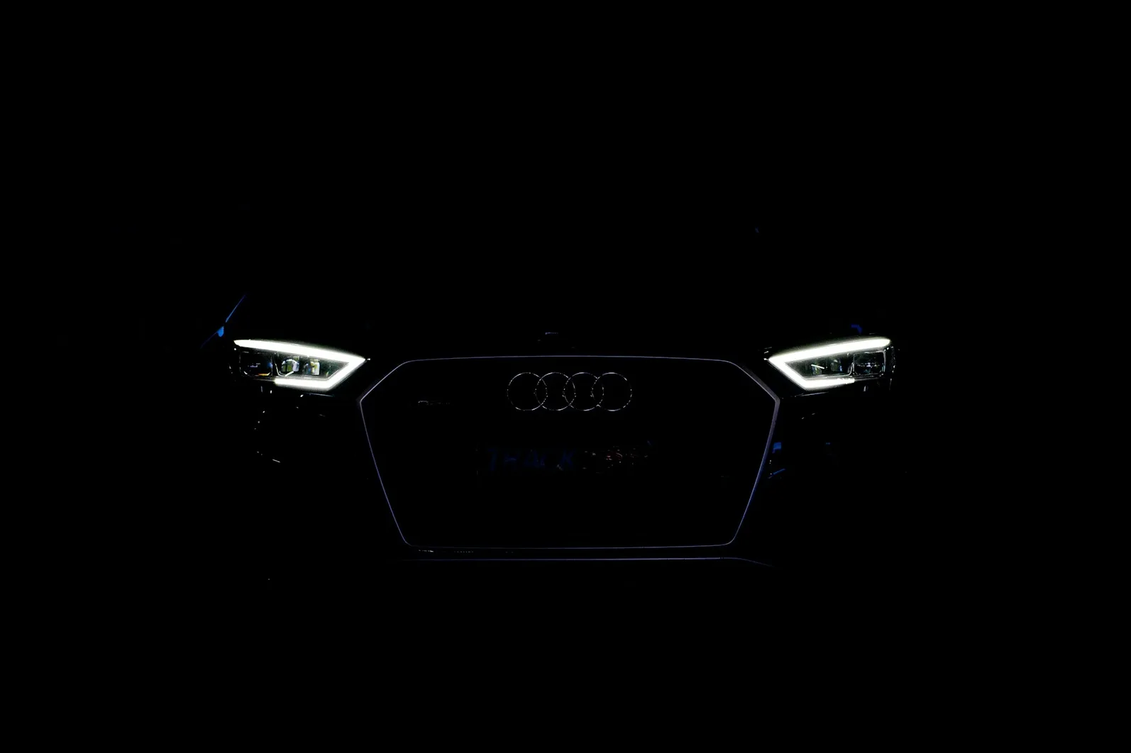 Prednji dio Audija RS3 Track-Focused Edition u mraku, sa istaknutim LED prednjim svjetlima i Audi logom.