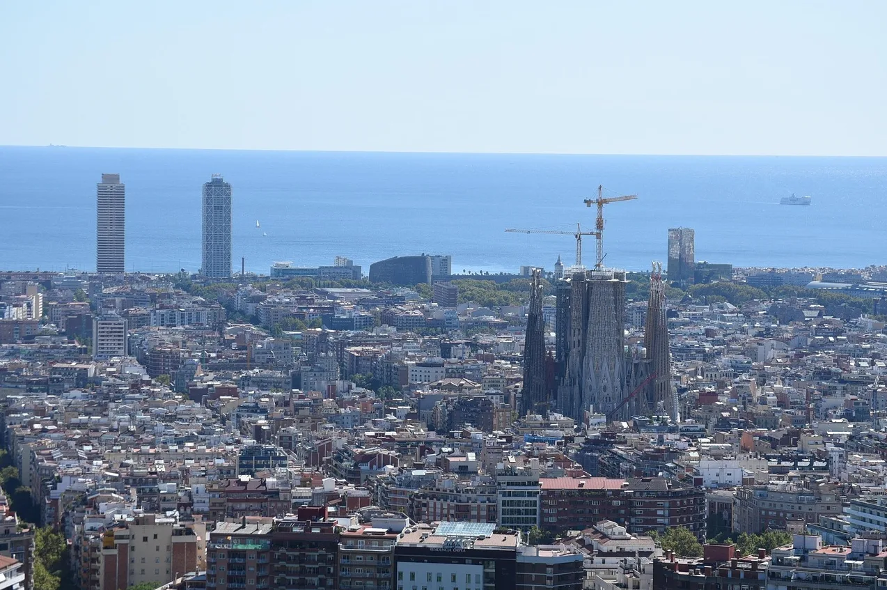 Panoramski pogled na grad Barselonu sa poznatom Sagrada Familia u izgradnji i neboderima u daljini pored mora.