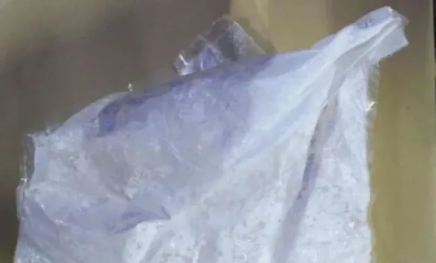 Detaljan prikaz bijele plastične vrećice koja sadrži neku vrstu bijelog praha ili kristala, djelimično prozirna i naborana.