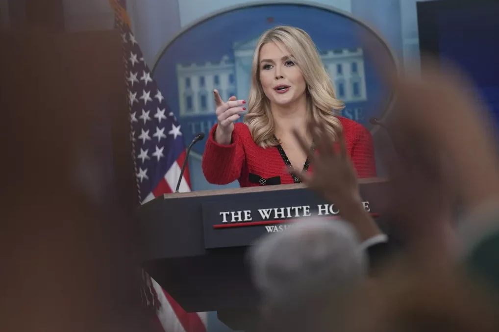 Predstavnica Bijele kuće, odjevena u crveni sako, obraća se novinarima ispred zastave Sjedinjenih Američkih Država.