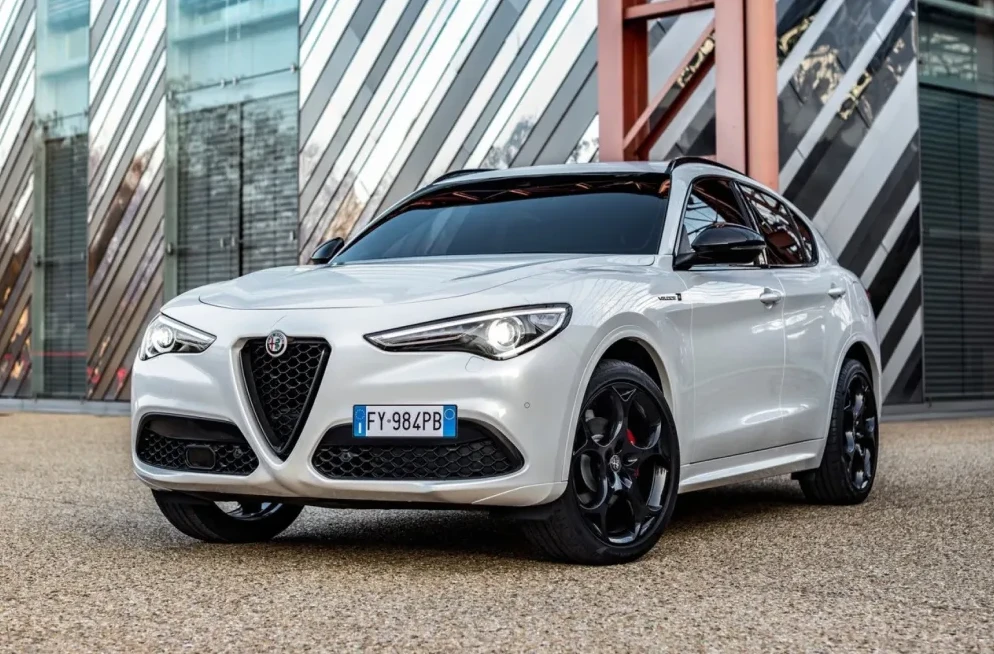 Prednji dio bijelog Alfa Romeo Stelvio SUV-a sa crnim aluminijskim felgama i sportskim detaljima.