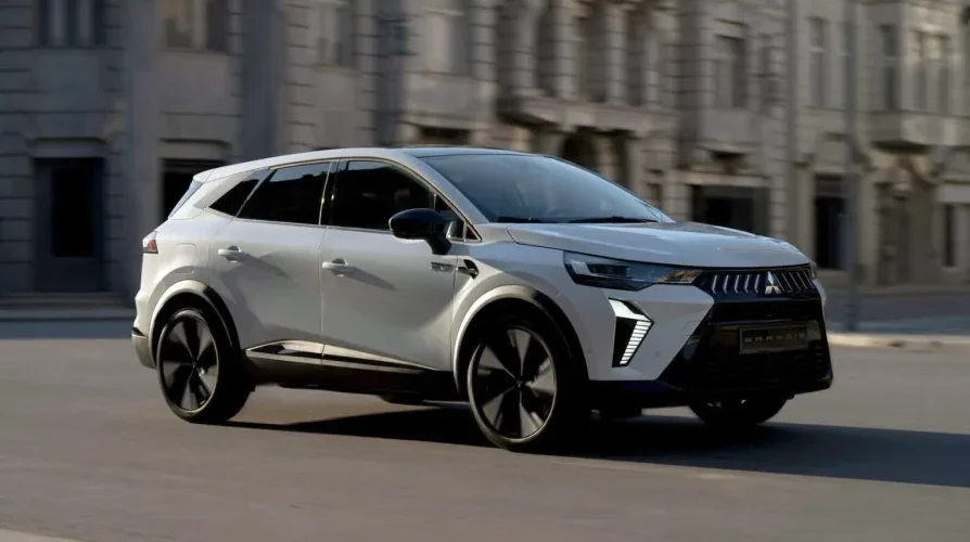 Bijeli Suzuki Grand Vitara SUV se vozi gradskom ulicom