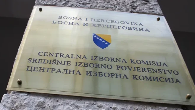 Zlatna ploča sa grbom Bosne i Hercegovine i natpisom "BOSNA I HERCEGOVINA" te "CENTRALNA IZBORNA KOMISIJA", "SREDIŠNJE IZBORNO POVJERENSTVO", "ЦЕНТРАЛНА ИЗБОРНА КОМИСИЈА".