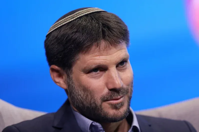 Muškarac sa kratkom smeđom kosom, bradom i kippahom na glavi, obučen u tamni sako i plavu košulju.