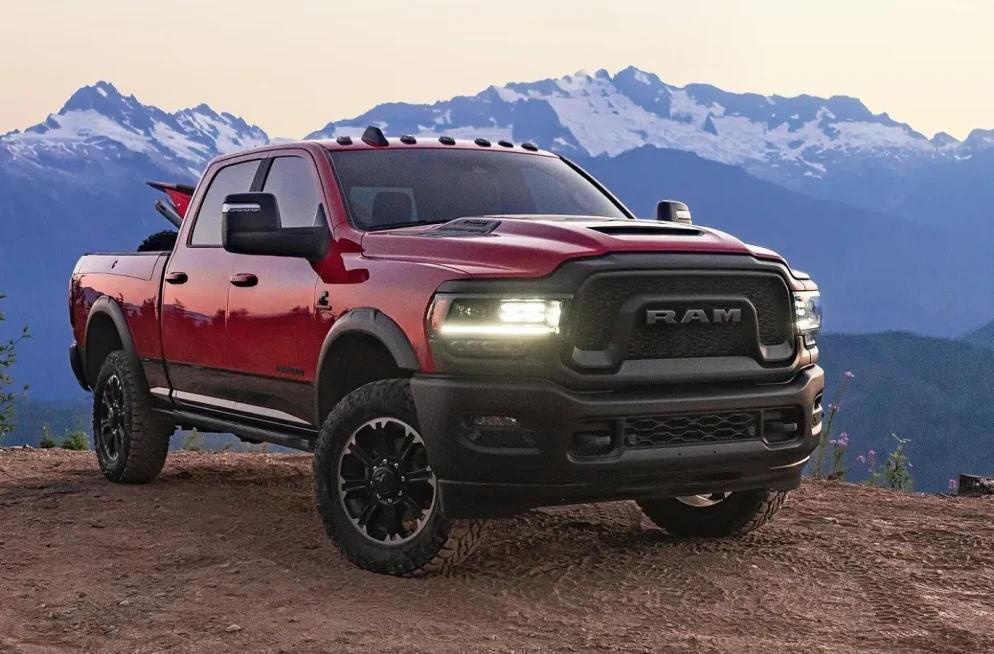 Crveni Ram Power Wagon parkiran na zemljanoj stazi s planinskim vrhom u pozadini.
