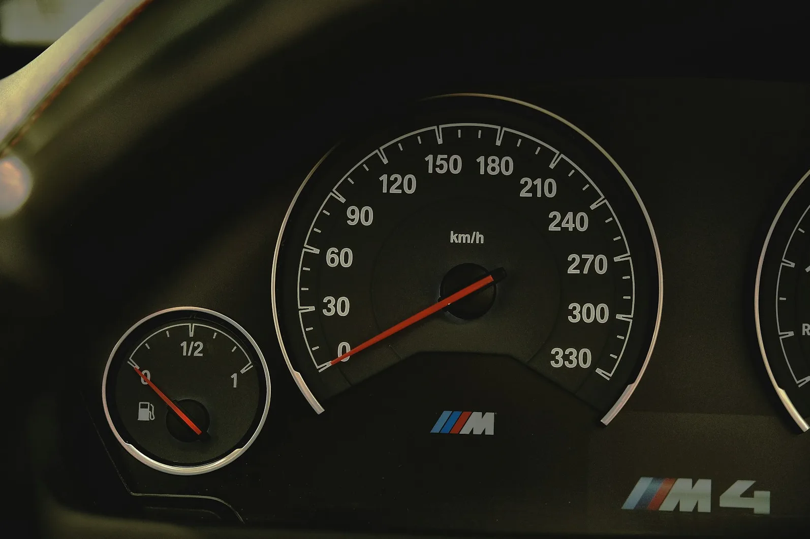 Unutrašnjost BMW M4 automobila sa osvijetljenim brzinometrom i pokazivačem goriva.
