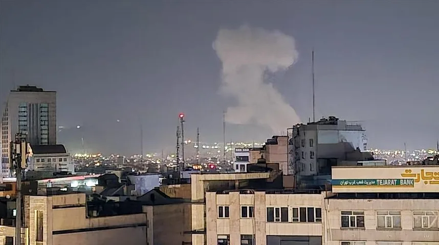 Gusta bijela dimna formacija iznad gradske panorame noću.