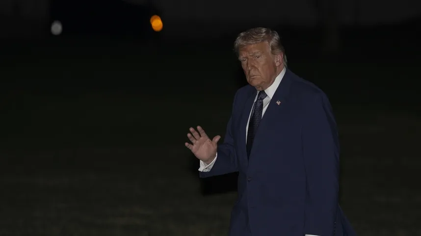 Donald Tramp u tamnoplavom odijelu podiže ruku u pozdrav.