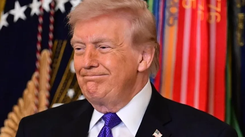 Donald Trump nosi tamno odijelo, bijelu košulju i ljubičastu kravatu dok gleda u stranu.