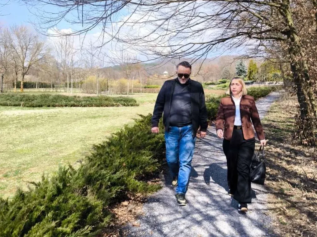 Muškarac i žena šetaju stazom u parku tokom proljeća.