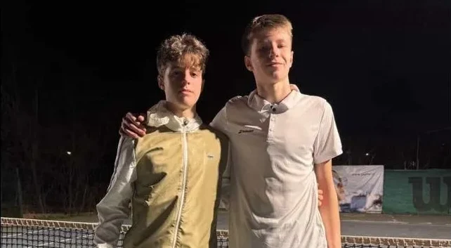 Dva mlada tenisera poziraju zagrljeni na teniskoj mreži