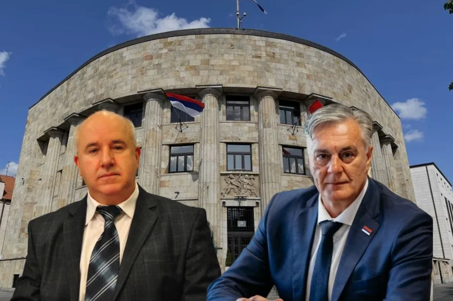 Dva muškarca u odijelima poziraju ispred zgrade Vlade Republike Srpske u Banjoj Luci, sa zastavama Republike Srpske istaknutim na zgradi.