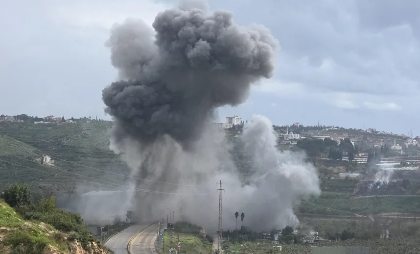 Eksplozija i gusti crni i sivi dim dižu se prema nebu iznad brdovitog terena naseljenog kućama i zgradama.