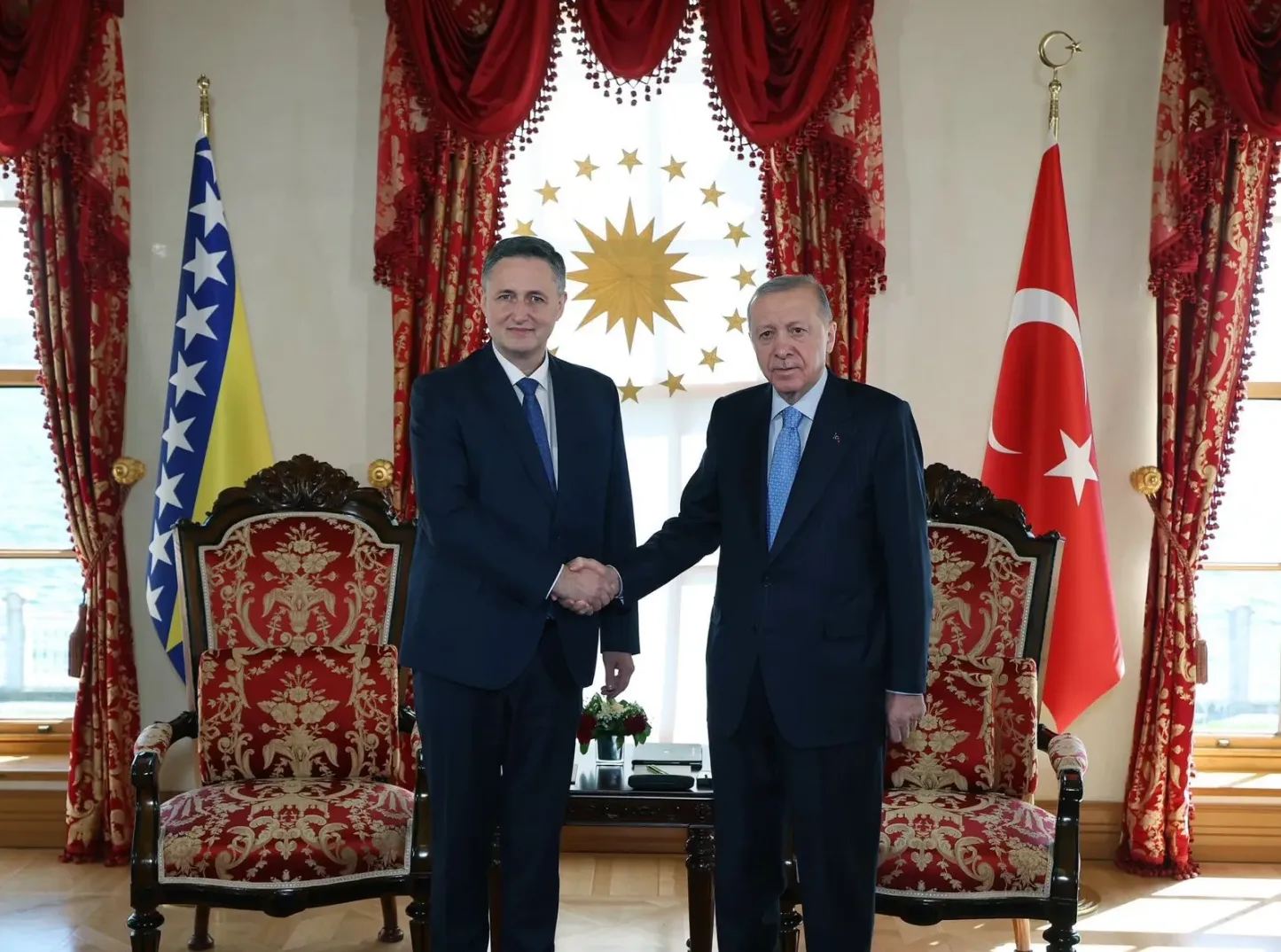 Predsjednik Turske Recep Tayyip Erdogan i bosanski zvaničnik se rukuju ispred zastava Bosne i Hercegovine i Turske.
