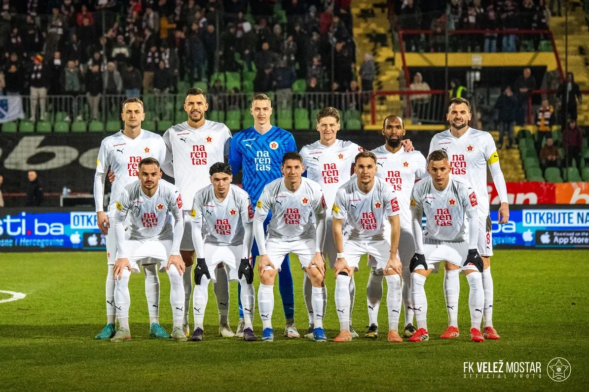 Fudbalski tim FK Velež Mostar pozira za timsku fotografiju na zelenom terenu.