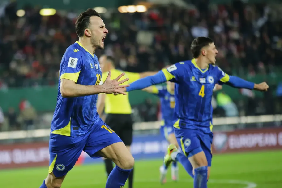 Fudbaler Bosne i Hercegovine u plavom dresu slavi postignut gol na utakmici.