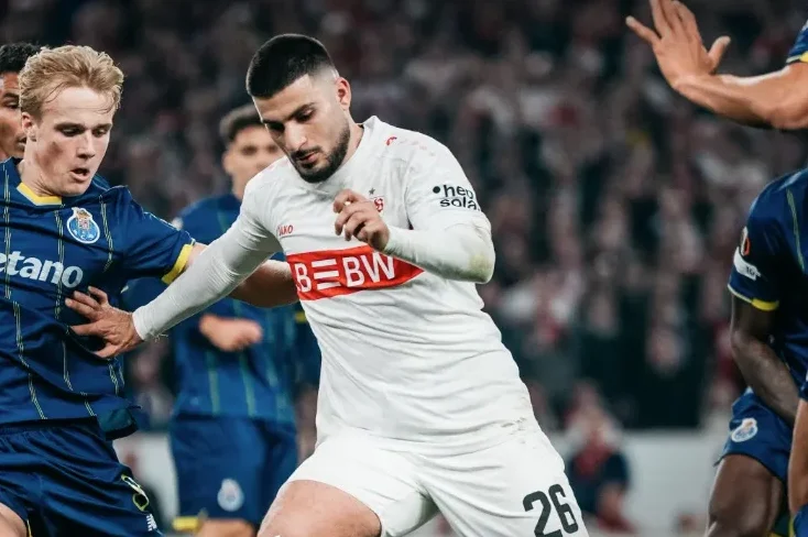 Fudbaler Stutgarta u bijelom dresu sa brojem 26 u duelu sa igračem Porta u plavom dresu.