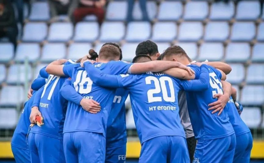 Fudbalski tim u plavim dresovima grli se na stadionu